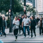 Crowd of people walking across a crosswalk