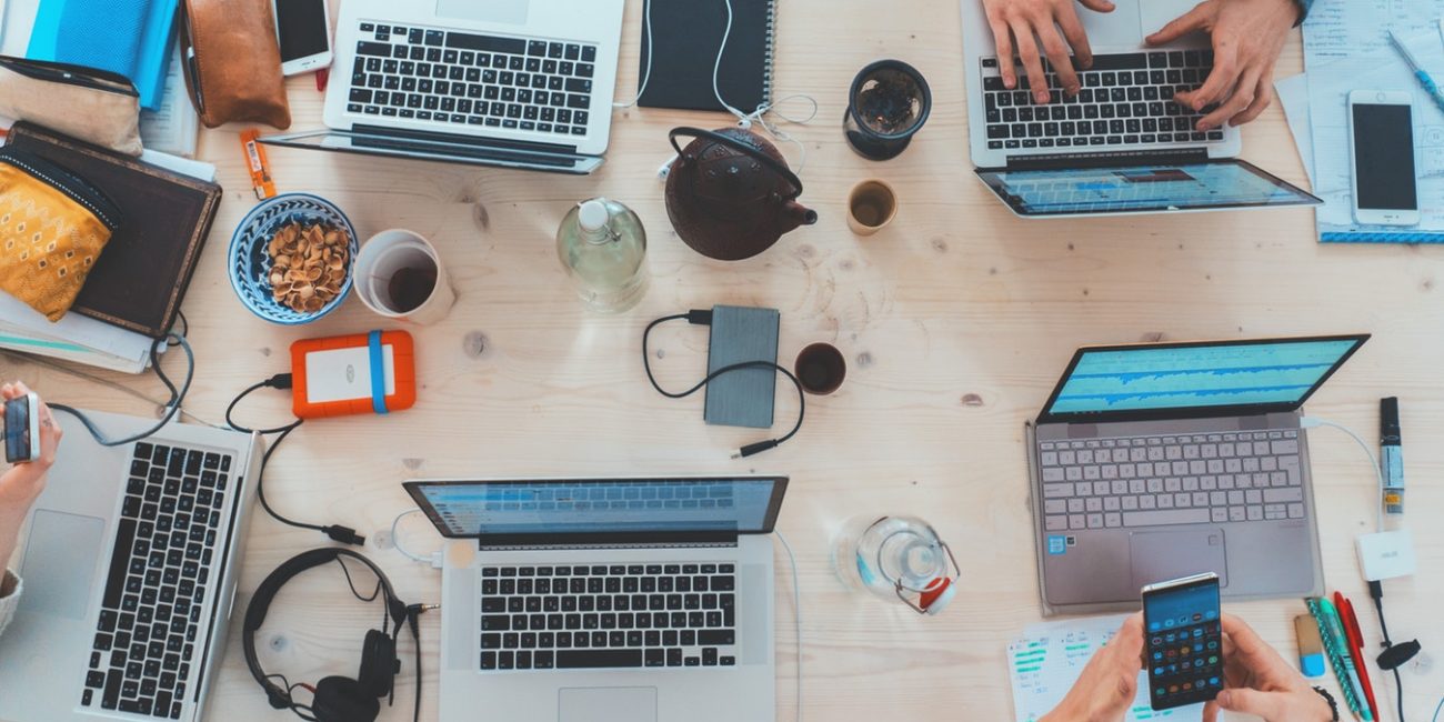 Bird eyes view of table filled with people working on laptops