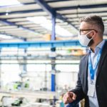 Man leaning on railing overseeing a manufacturing facility