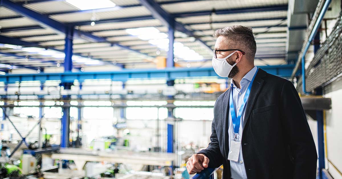 Man leaning on railing overseeing a manufacturing facility