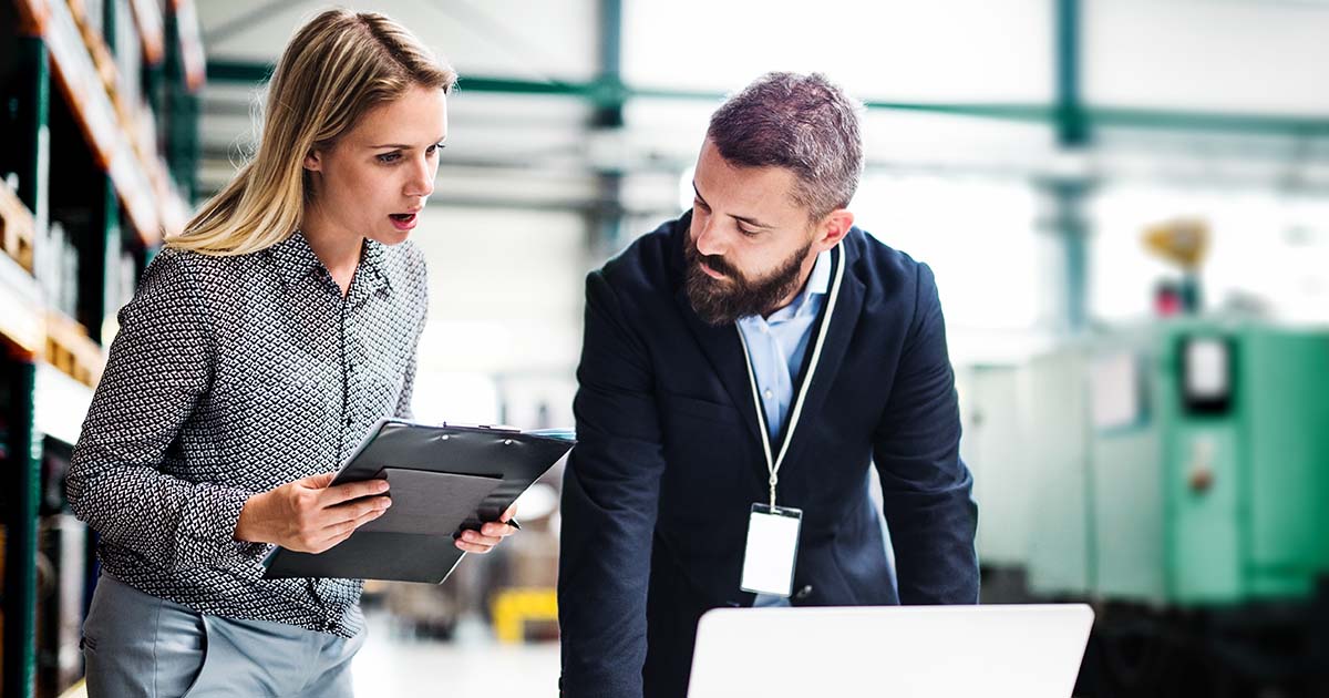 Man and woman standing together and discussing something on a laptop