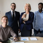 Group of young business professionals and CEO standing around a conference room table