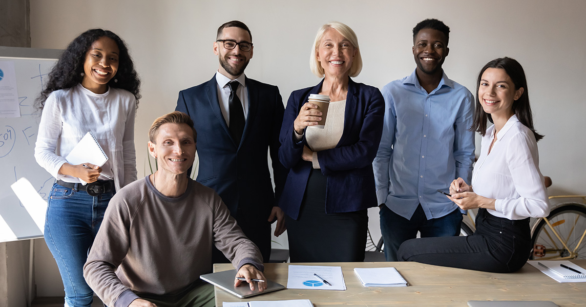 Group of young business professionals and CEO standing around a conference room table