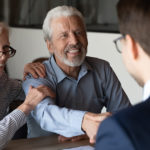 Older couple gleefully shaking hands with a younger gentleman