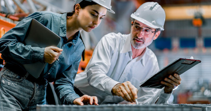 Two professional engineers using clipboards while discussing work in a steel metal manufacture factory plant